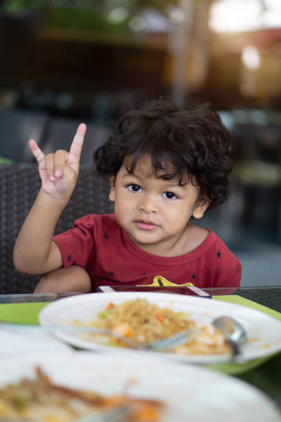 istock Portrait Of Cute Boy Gesturing While Sitting On Chair At Table In Restaurant 1138340899