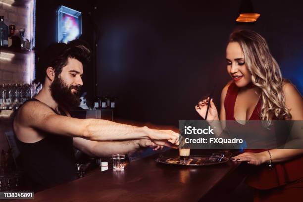 A Beautiful Girl In A Red Dress Is Holding A Straw And Waiting For The Barman To Make A Cocktail Stock Photo - Download Image Now