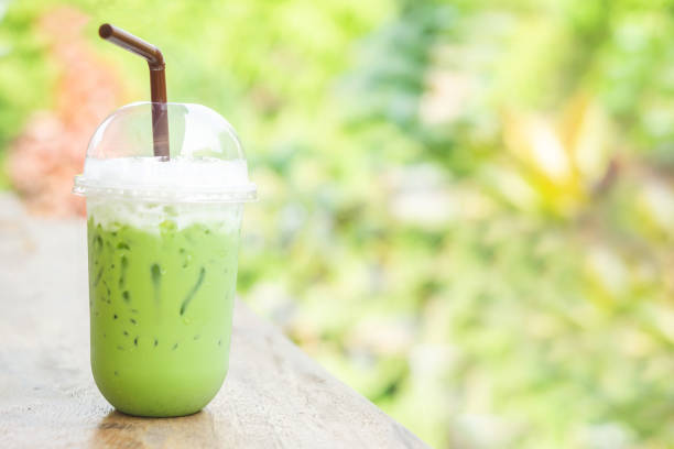 iced green tea latte with milk in plastic cup on wooden table cafe