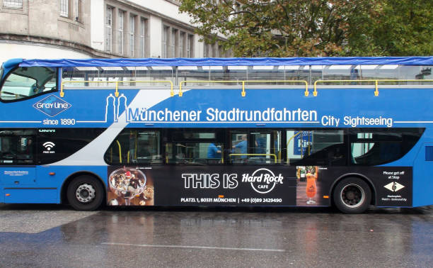 View Of People, Advertisement Sign, Building Exterior And Munich Sightseeing Double Decker Bus During The Day In Munich Bavaria Germany Europe