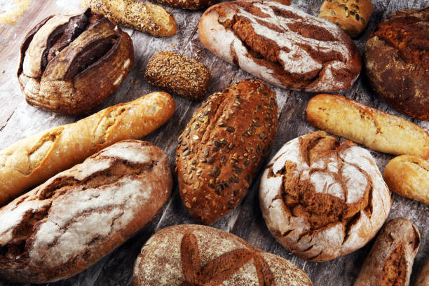 istock Different kinds of bread and bread rolls on board from above. Kitchen or bakery 1138350112