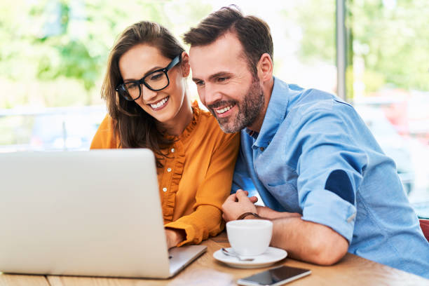 istock Happy couple using laptop at cafe enjoying time together 1138353658