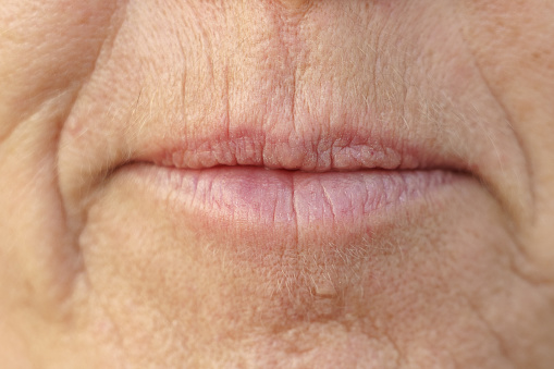 Extreme Closeup on the mouth of a middle-aged brunette woman with her mouth closed and a serious expression