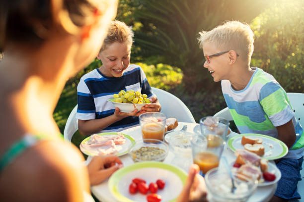 bambini felici che mangiano colazione fresca all'aperto - family grape foto e immagini stock
