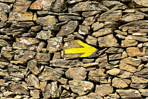 flèche jaune sur le vieux mur, indicateur de direction sur les itinéraires de pèlerin le chemin de saint-jacques. - religious mark photos photos et images de collection