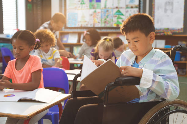 istock Schoolboy studying in classroom while sitting at wheelchair 1138358681
