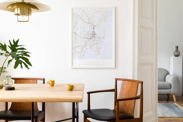 Stylish and eclectic dining room interior with mock up poster map, sharing table design chairs, gold pedant lamp and elegant sofa in second space. White walls, wooden parquet. Tropical leafs in vase. Stylish and modern dining room interior with mock up poster. Eclectic decor. wooden bleachers stock pictures, royalty-free photos & images