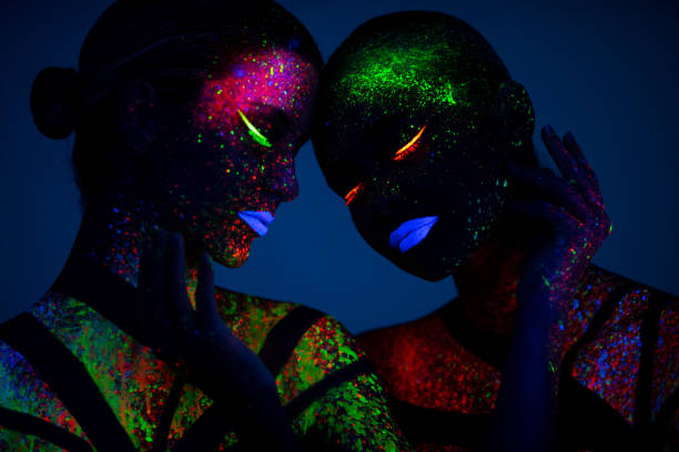 Two young women painted with fluorescent colors