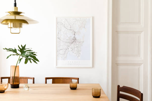Stylish and modern dining room interior with mock up poster map, sharing table design chairs, gold pedant lamp and cups of coffee. White walls, wooden parquet. Tropical leafs in vase. Eclectic decor. Stylish and modern dining room interior with mock up poster. Eclectic decor. wooden bleachers stock pictures, royalty-free photos & images