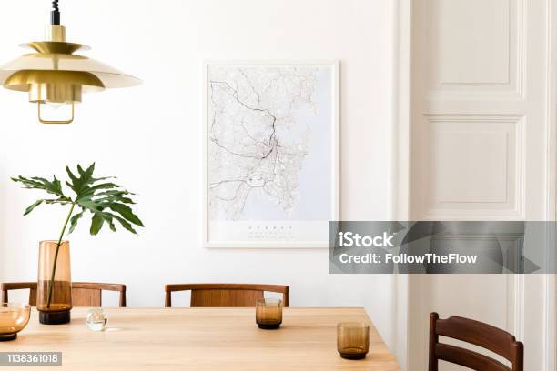 Stylish And Modern Dining Room Interior With Mock Up Poster Map Sharing Table Design Chairs Gold Pedant Lamp And Cups Of Coffee White Walls Wooden Parquet Tropical Leafs In Vase Eclectic Decor Stock Photo - Download Image Now