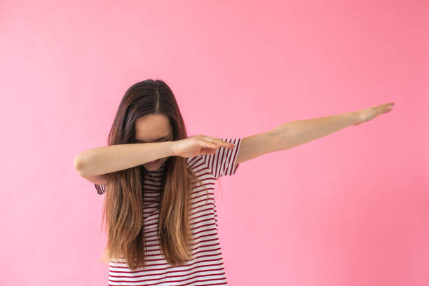 Young girl doing dab dance gesture. Portrait of young brunette girl doing dab dance gesture on pink background. Lifestyle concept dab dance photos stock pictures, royalty-free photos & images