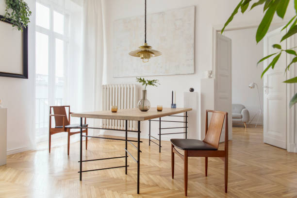istock Eclectic and elegant dining room interior with design sharing table, chairs, gold pedant lamp, abstract paintings and stylish accessories. View to living room. Eclectic decor. Brown wooden parquet. 1138361266