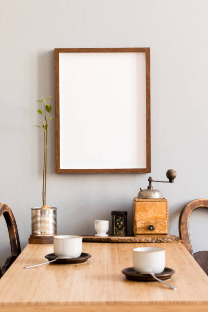 istock Stylish and modern interior design of kitchen space with small wooden table with mock up photo frame, avocado plant, accessories and cups of coffee. Scandinavian and cozy room decor. 1138361529