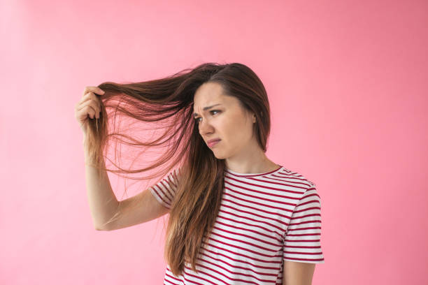 The girl is not happy with her hair The girl is not happy with her hair and shows split ends or dandruff or dry hair or other problems. slippery stock pictures, royalty-free photos & images