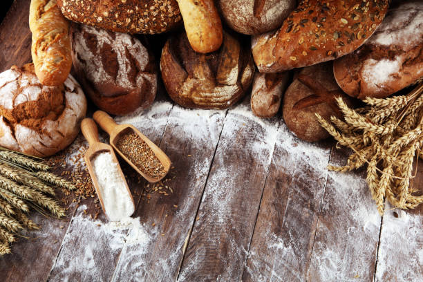 istock Different kinds of bread and bread rolls on board from above. Kitchen or bakery 1138362083