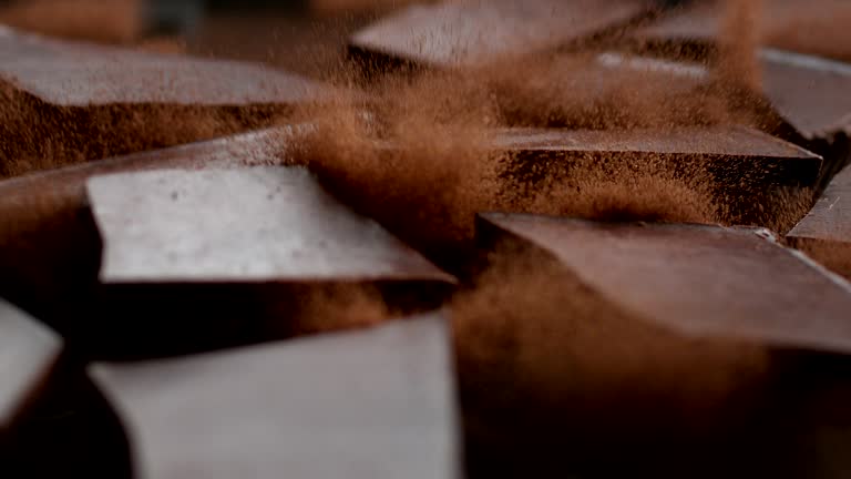 Chocolate cubes cracking on cacao powder. Cocoa explosions