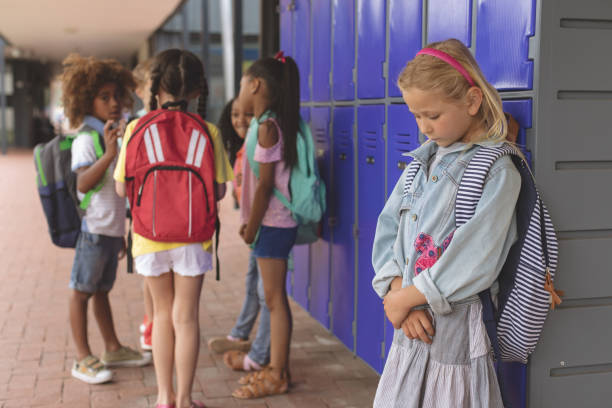 istock Sad schoolgirl standing in corridor while others school kids interacting with each other 1138362476
