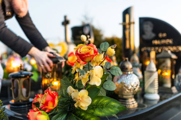 artificial and real flowers and lit candles lying on the tombstone in the cemetery. - brightly lit imagens e fotografias de stock