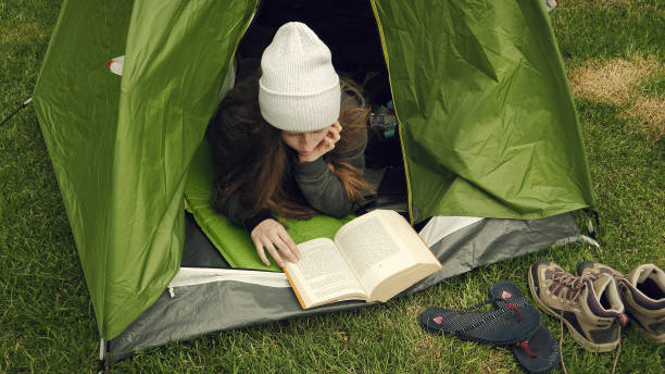 istock Camping activities. Woman reading a book in tent 1138363651