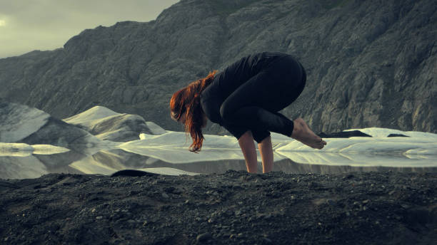 istock Crow pose. Woman doing yoga on glacier 1138364149