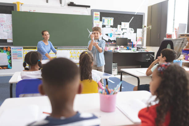 istock Schoolboy explaining to his classmates about windmill in classroom 1138366929
