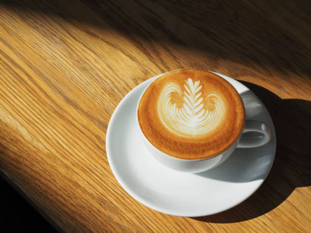 istock latte or Cappuccino art coffee cup top view on wood table with sunlight in cafe. 1138368866
