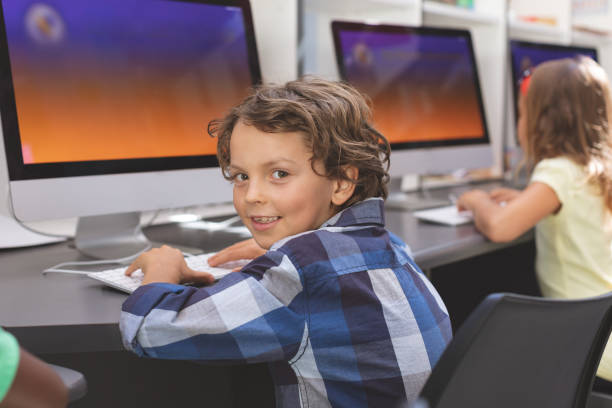 istock Happy schoolboy sitting in computer room 1138369226