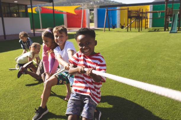 gruppe von schulkindern, die tauziehen spielen - kinderspielplatz stock-fotos und bilder