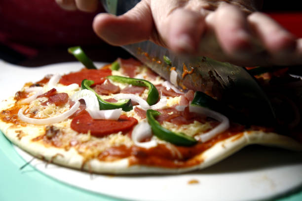 istock Ham, pepperoni, cheese with green bell pepper pizza being sliced 1138371234