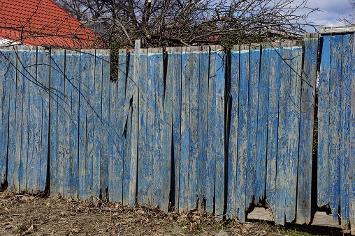 part of a blue wooden old fence from planks on a rural street