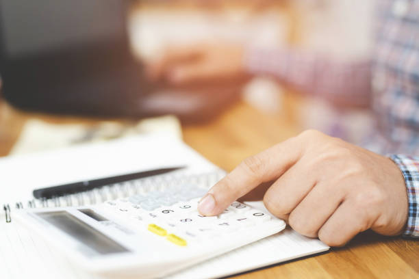 istock Close up businessman hand using calculator and writing in a notebook counting making notes Accounting at doing finance at home office. Savings finances concept. note pad 1138373806