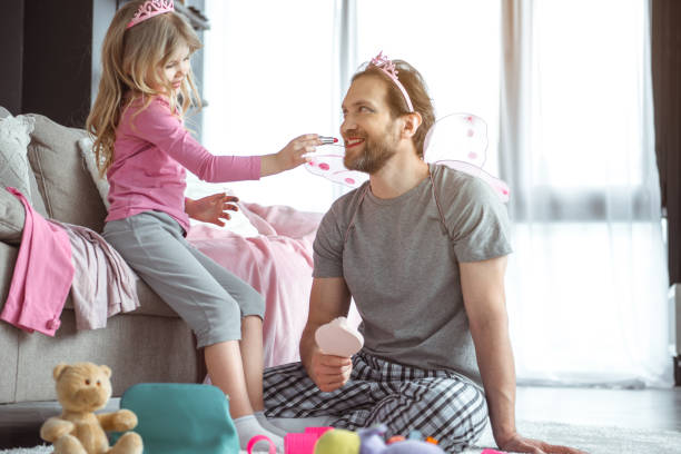 istock Cheerful kid applying lipstick on her father 1138375585