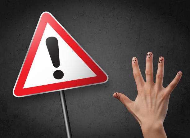 istock Happy smiley fingers looking at triangle warning sign with exclamation mark 1138376377
