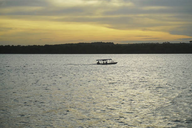 Little fishing boat accross the lake at the sunset