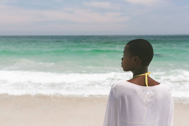 istock Woman relaxing and standing on beach on a sunny day 1138378139