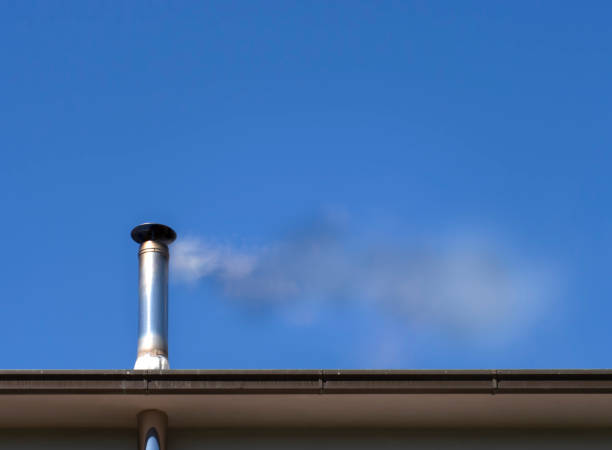 istock Smoke and pollution issue from a wood burning stove chimney, into bright blue summery sky. 1138378521