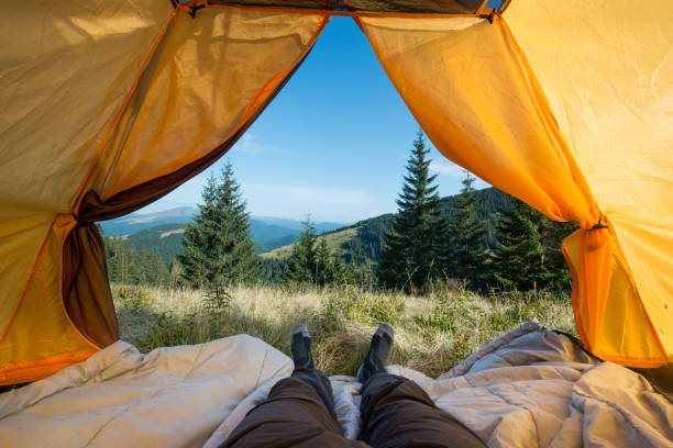 jambes du voyageur dans une tente de camping à l'extérieur - bâtiment vu de lextérieur photos et images de collection