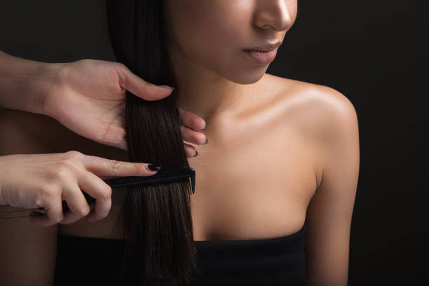 Young woman visiting professional haircutter Locks care. Close up of hairdresser arms combing silky female hair Combing stock pictures, royalty-free photos & images