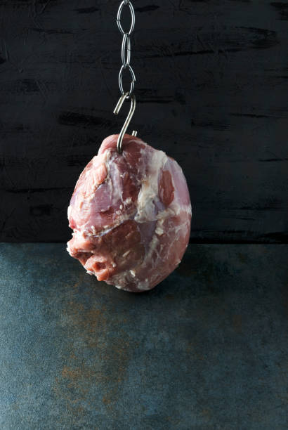 istock Fresh meat on hook against black background.Vertical photo 1138382247