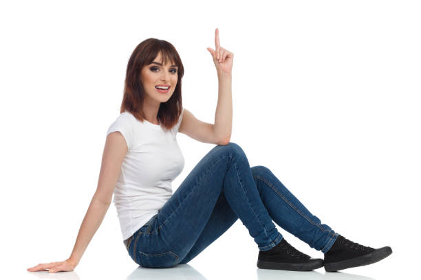 istock Young Woman Is Sitting On Floor, Pointing Up And Talking 1138382374