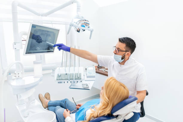 Dentist explaining tooth x-rays to a female patient Dentist holding patient's orthopantogram dental cavity photos stock pictures, royalty-free photos & images
