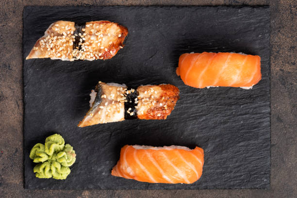 istock Sushi rolls and sashimi in a black stone plate. 1138384136