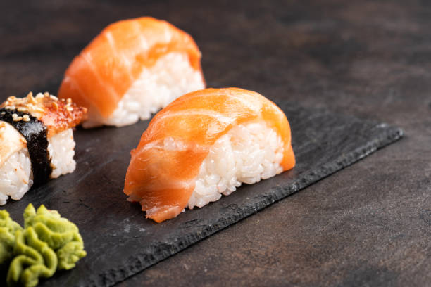 istock Sushi rolls and sashimi in a black stone plate. 1138384585