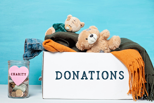 Coins and banknotes in glass money jar with label and a box with donations, charity concept.