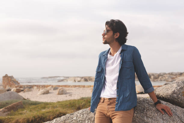 istock Caucasian man standing and leaning at beach on a sunny day 1138386233