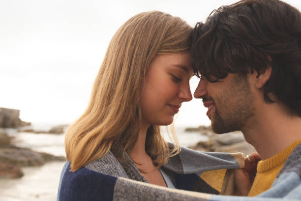 istock Caucasian couple wrapped in blanket standing at  beach 1138386545