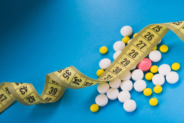 istock Yellow round vitamin pills with measuring tape 1138386571