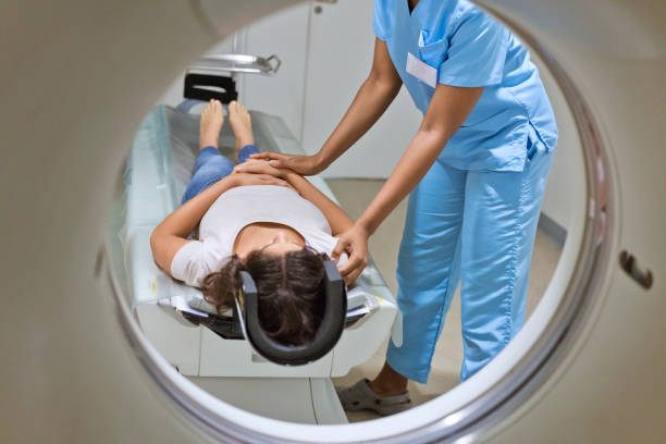 Female nurse preparing patient for MRI scan Low section of female nurse preparing woman for MRI scan. Young patient is undergoing through CAT scan. They are at hospital. radiotherapy stock pictures, royalty-free photos & images