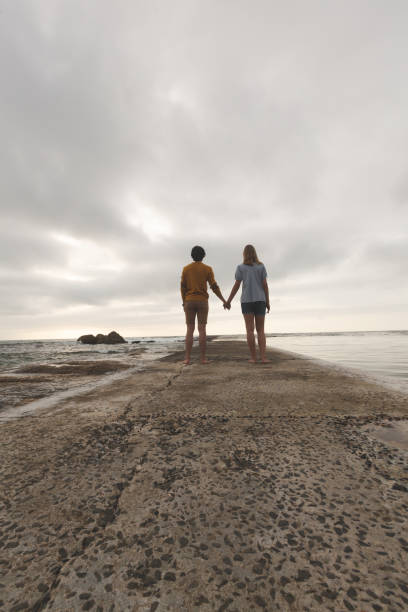 istock Caucasian couple standing on rock near beach 1138387773