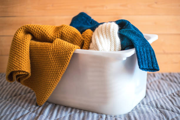 istock Container with laundry on sofa against wooden background. 1138387843